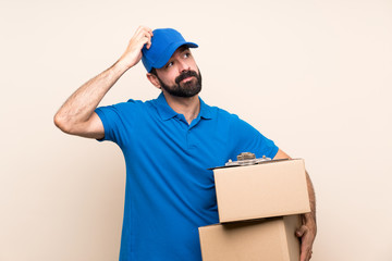 Delivery man with beard over isolated background having doubts while scratching head