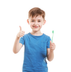 Portrait of little boy with toothbrush showing thumb-up on white background