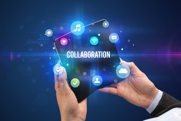 Businessman holding a foldable smartphone with COLLABORATION inscription, social media concept
