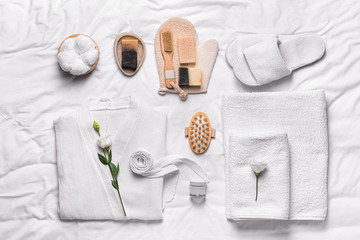 Clean bathrobe with spa supplies on white background - obrazy, fototapety, plakaty