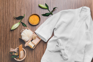 Clean bathrobe with spa supplies on wooden background