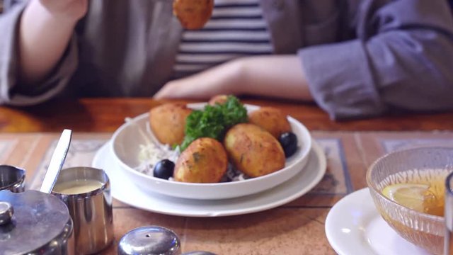 Woman in cropped view eating salted cod food, Pasteis de Bacalhau, Bacalao, Bacallao, delicious Portuguese dishes meal in Macau restaurant, lifestyle.