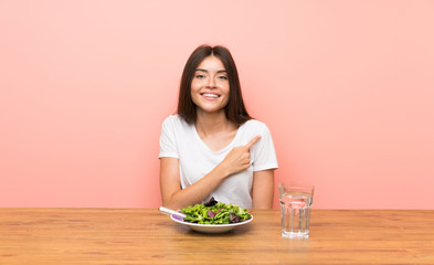 Young woman with a salad pointing to the side to present a product