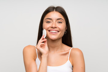 Pretty young woman removing makeup from her face with cotton pad