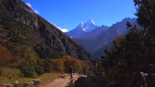 Active hikers hiking, enjoying the view, looking at Himalaya mountains landscape.Tracking to Everest base camp  with Ama Dablam mount view. Travel sport lifestyle concept. Static shot, cam slowly move