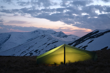 Green tent on amazing sunset mountains background. Landscape photography, travel concept