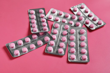 Blisters with pills on color background