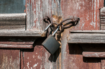 Old vintage weathered gunge locked padlock closeup on aged wooden door