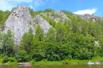 A group of people floating on the river in inflatable catamarans among the beautiful rocks and...