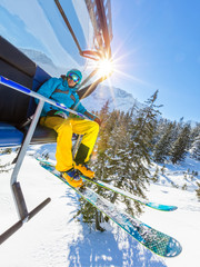 Skier sitting at ski lift in high mountains during sunny day