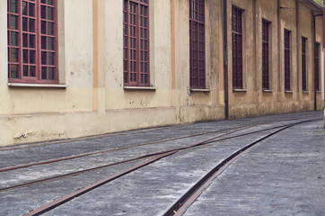 train tracks on a gray floor next to a yellow workshop ship