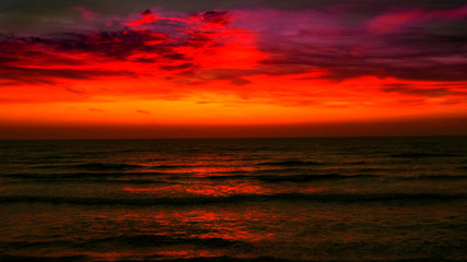 Fototapeta na wymiar Sunrise over the sea. Fiery red sky and metallic gray water. Bright path to the shore.