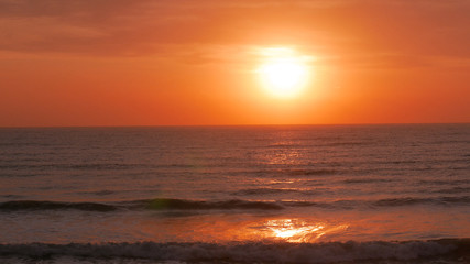 Sunrise over the sea. The sun is showing and coloring the sky in golden yellow. Bright path to the shore.