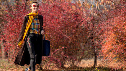  Fashionable autumn woman in trendy fall outfit walking in autumn park