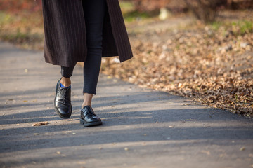 Fototapeta na wymiar Closeup legs fashionable woman wear black shoes and brown coat. Stylish fall outfit