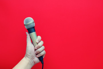 hand holding microphone on red background