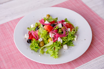 Tasty fresh Greek salad on white wooden table,