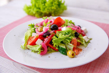 Tasty fresh Greek salad on white wooden table,