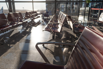 An empty hall of an airport terminal, chairs reflecting bright morning light. Concept of tourism slowdown or airport personnel strike action.