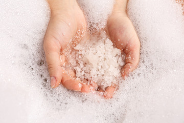 white bath salt in a female hand dissolves in water