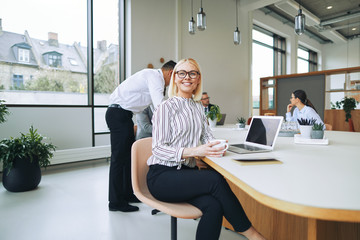 Smiling young businesswoman sitting in a boardroom drinking coff