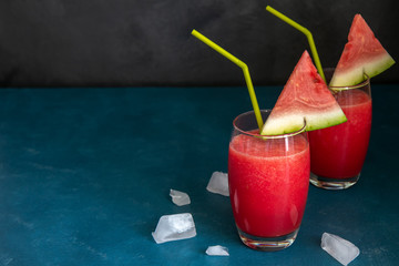 Fototapeta na wymiar Two watermelon smoothies in a transparent glass on a dark background