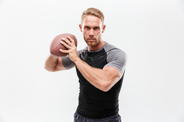 Focused young fit sportsman holding rugby ball isolated