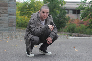 Man Crouching Outdoors Wearing a Gray Jacket