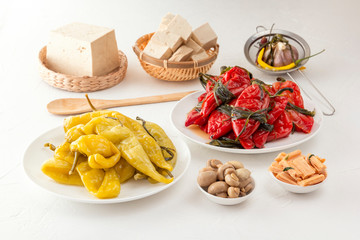 Traditional Korean fermented food - red hot peppers with herbs, yellow salted peppers and tofu bean curd on a white table