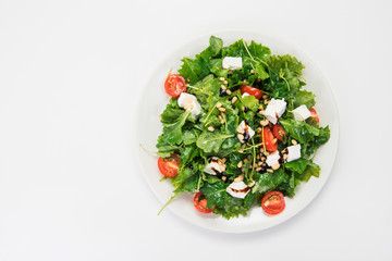 Green salad with vegetables: greens, arugula, tomato, cheese, pine nuts and sauce
