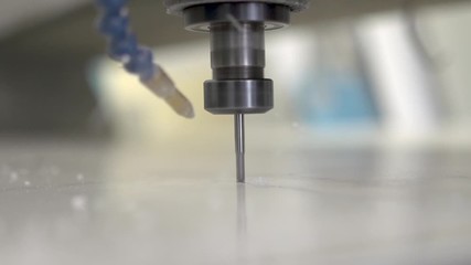 Computer numerical control machine router completing a small metal project. Close up view of a silver end mill bit spinning.  Slow motion.