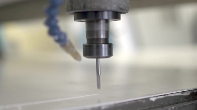 Close up of an end mill bit in action. Computer numerical control machine is getting started. Slow motion. 