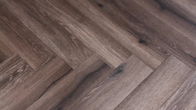 A slow panning shot of a wooden floor in a herringbone pattern.