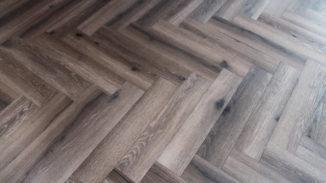 A slow panning shot of a wooden floor in a herringbone pattern.
