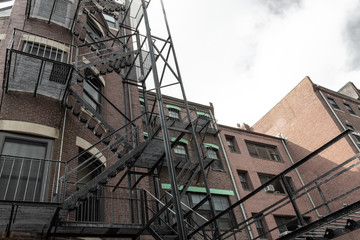 Layers of metal fire escapes on the exterior rear of old brick apartment building, horizontal aspect