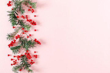 Christmas modern composition. Fir tree branches, red berries, Xmas decorations on pastel pink background. Christmas, New Year, winter concept. Flat lay, top view, copy space