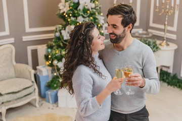 Shot of cool man and woman making wishes, with glasses of champange in their hands.