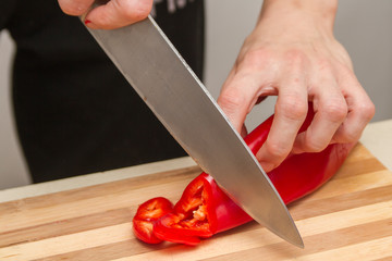 Chef slicing red paprika on a table