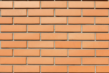 The texture of the wall of a new red brick house lit by the sun. Background