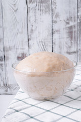 Yeast dough in a glass bowl ready to be formed into bakery products against white background