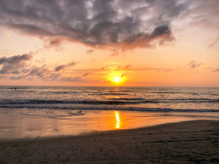 Colorful ocean beach sunset facing the sun with deep clouded sky. Beautiful cloudscape over the sea during sunset. 