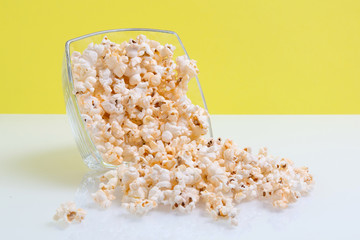 popcorn in a glass bowl on yellow background