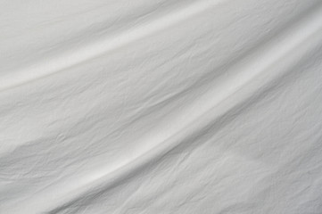 A gentle curve arcs through the frame from top right to bottom left of muslin cloth backdrop with small wrinkles.