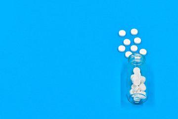 Composition at an angle with medicinal pills or drugs and glass bottle on a blue background, healthcare and pills concept. Flatlay with copy space