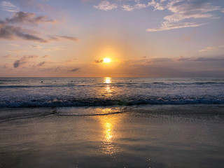 Colorful ocean beach sunset facing the sun with deep clouded sky. Beautiful cloudscape over the sea during sunset. 