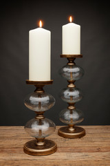 2 glass candle holders and glowing candles, shot on a wooden table