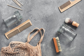 Eco friendly objects. Cotton bag, glass jar, wooden comb, wooden shaving brush, cuticle pusher, brush on a gray background. Zero waste. Flat lay, top view.