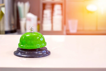 Restaurant green bell with bokeh on white table.