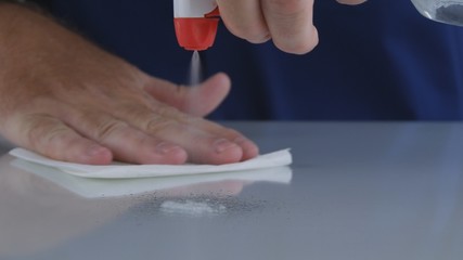 Man Cleaning Table Glass Surface with a Wet Wipe and a Spray