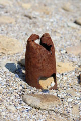  A rusty pipe dug in the sand. Beach pollution. Dangerous pin from the ground